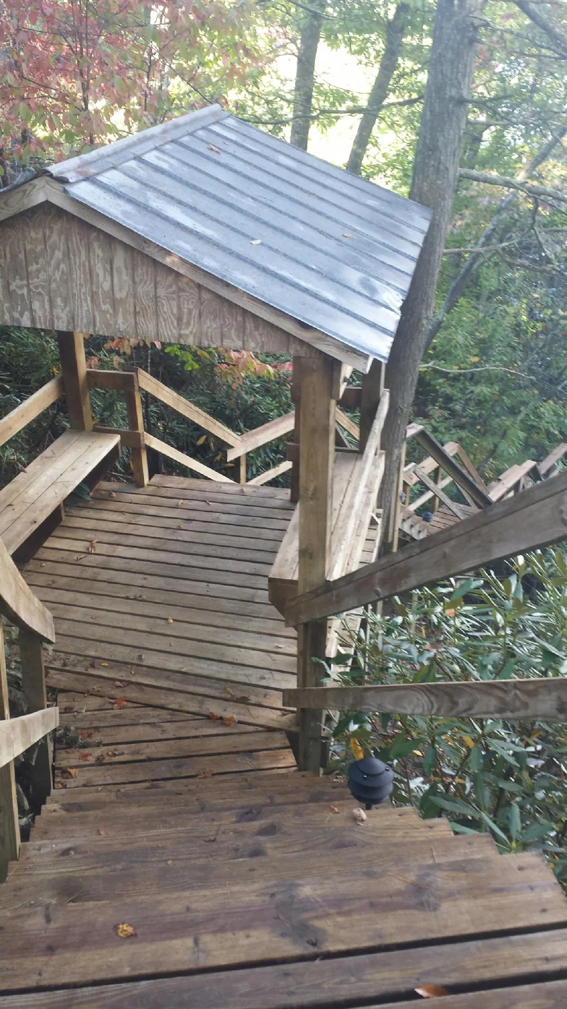 Metal roofed shelter over wooden steps on a wooded walkway — Skylight Repair & Installation work by our crew in Valley Falls