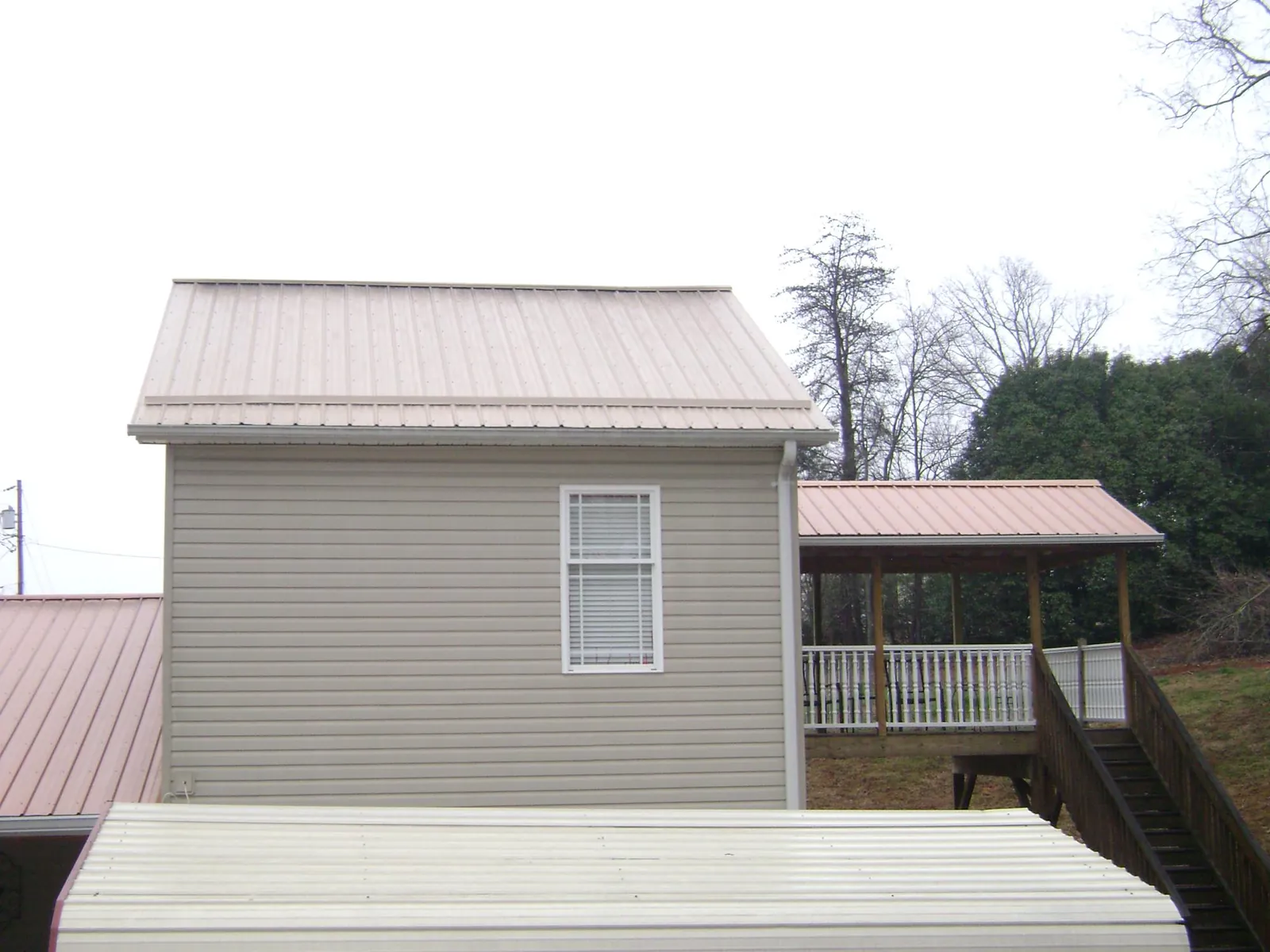 Tan metal roofs on a two story addition and attached porch in Valley Falls