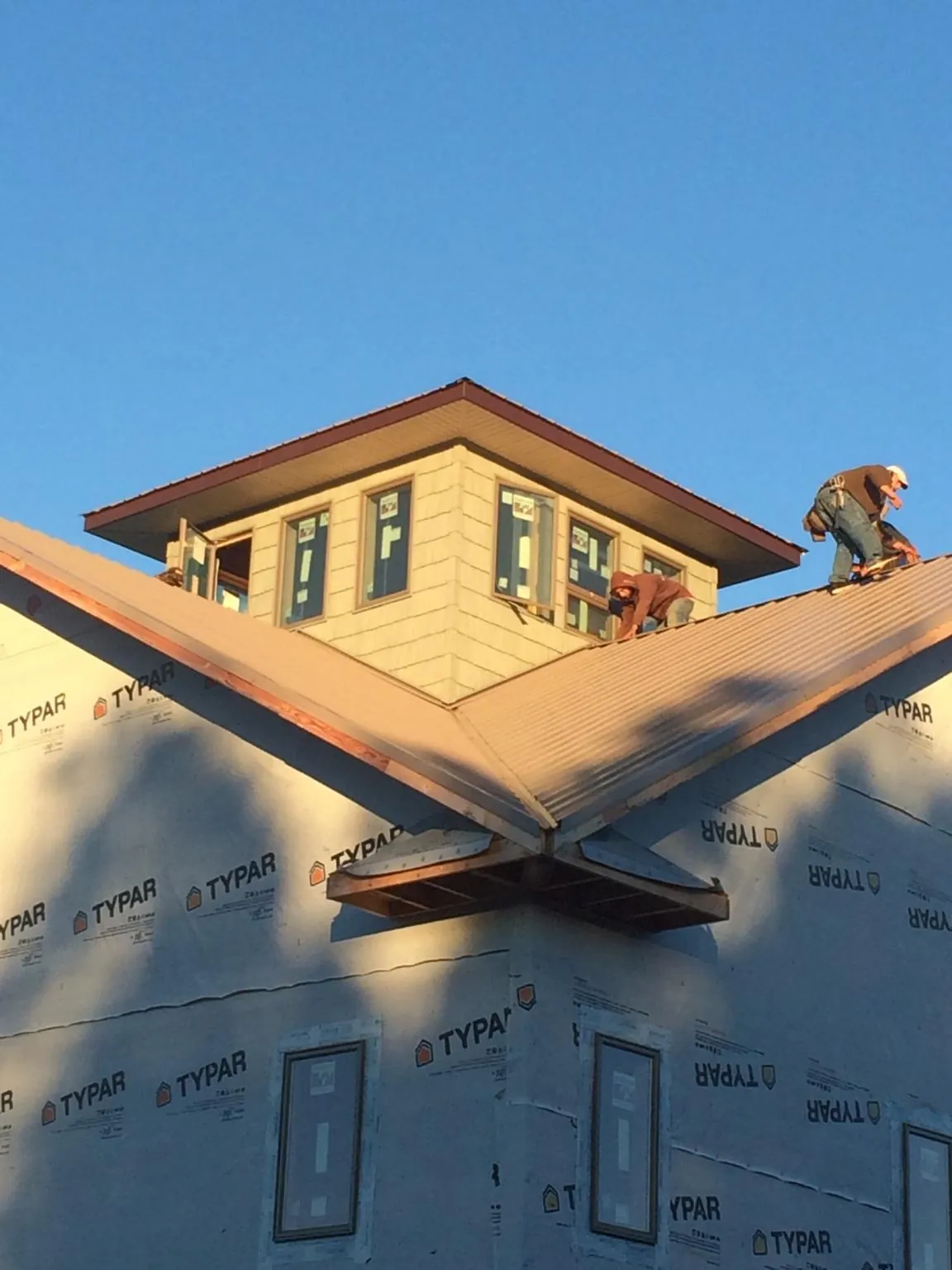 Roofers working around a rooftop cupola on a new metal roof at sunset — Roof Waterproofing in Valley Falls by Roofing Brothers